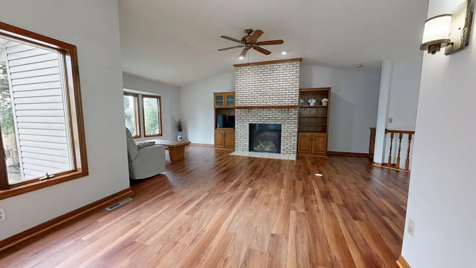 Sala com piso de madeira, lareira de tijolos e estante embutida